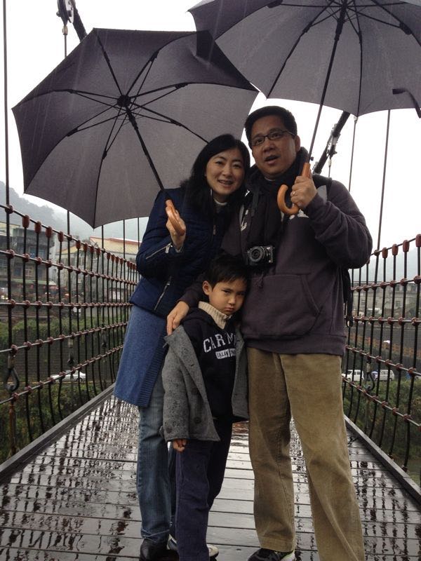 A photo of a young Philip on a bridge with his parents who are holding umbrellas, where he looks visible upset.