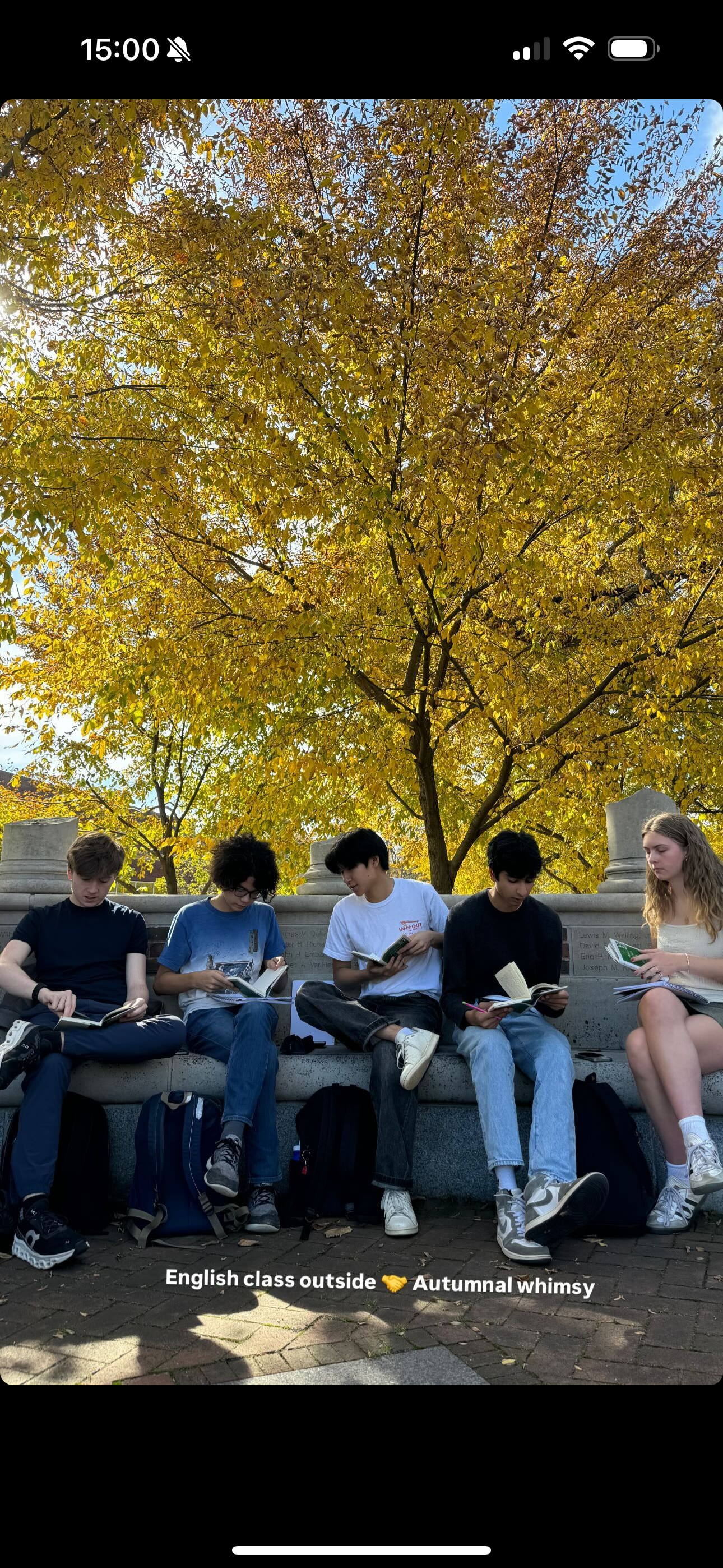 A screenshot from an Instagram story by Ms. Foushee of Philip and four others from his English 300 class that took place outside on a bright autumn day with yellow trees in the background.